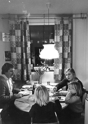 Två vuxna och två barn sitter runt ett bord och äter kvällsmat, 1970-tal