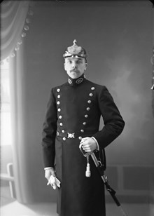 Porträtt av Erik Jonsson i polisuniform och med pickelhuva.