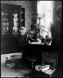 Porträtt av författarinnan Alfhild Agrell. Interiör med skrivbord och bokskåp