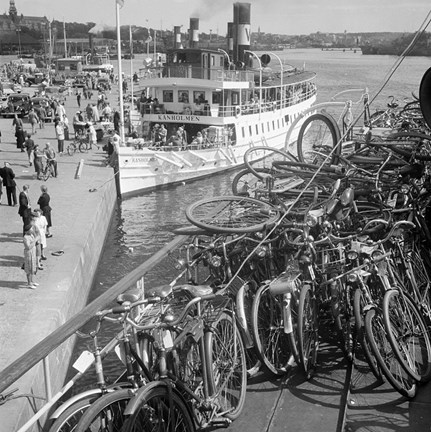 Ångbåten Kanholmen vid kajen intill Strandvägen 1. En mängd cyklar är lastade på båten i förgrunden.