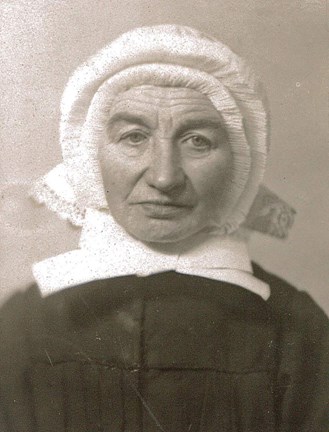 Porträtt i svartvitt av syster Celsa Cäecilia Stelter. Hon är medelålders, ser lite sliten ut och är klädd i svart dräkt, med vit hätta som täcker hela håret. Hättan har krusade kanter och under hakan en stor vit rosett.