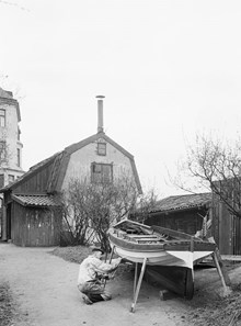Gårdssidan av Parmmätargatan 19. En man målar båten. Platsen motsvarar nuvarande adress Kungsklippan - Parmätargatan .