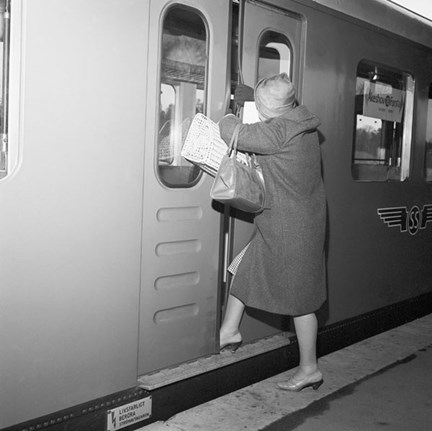 Kvinna med packning pressar isär dörrarna till en tunnelbanevagn för att komma in