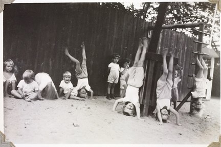 Svartvit bild av barn som leker, står på huvudet och hänger i knävecken.