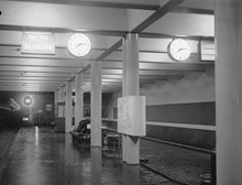 Station Södra Bantorget. Perrrong med klocka, distinationsskyltar och anslagstavla, sedd från söder
