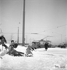 Trådbuss i snö vid Gullmarsplan 1952. Lekande barn