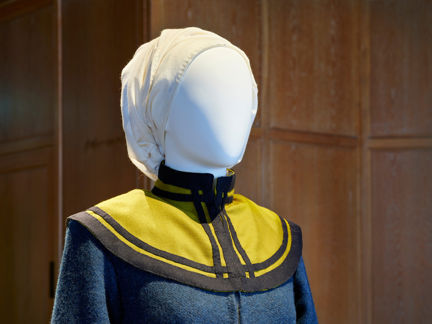 Foto av en dockas huvud framifrån klädd i återskapad dräkt