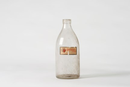 Flaska, ursprungligen använd till mjölk, av ofärgat, formpressat glas.