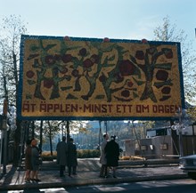 Stor skylt med mosaik av äpplen uppställd i Kungsträdgården vid Hamngatan. Trädmotiv. Text: "ÄT ÄPPLEN-MINST ETT OM DAGEN"