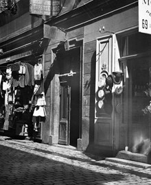 Utanför butikerna vid Västerlånggatan 69 hänger kläder och hattar till försäljning