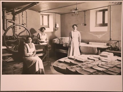 Svartvitt fotografi på tre kvinnor i mangelrum från Hemmet för gamla