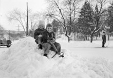 Två barn åker kälke i snön