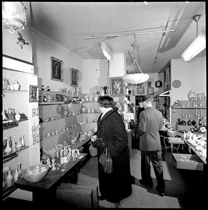 En butik med hyllor med inredningsföremål. en man och en kvinna tittar runt i butiken.