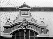 Hötorgshallen före rivningen 1954. Byggnadsdetaljer vid taket med årtalet 1882 då saluhallen byggdes och vapensköld med St. Erik