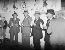 Män i kostym och hatt äter och dricker mjölk ur flaska i samband med Bondens dag år 1938.