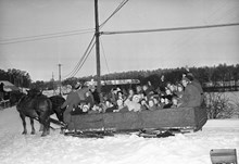 Hästar spända framför en släde, full med barn från Solna