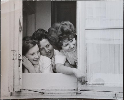 Svartvitt fotografi på tre barnsköterskor som tittar ut genom ett fönster hos Föreningen Barnavård