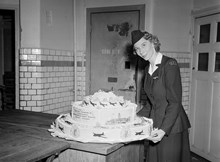 Regeringsgatan 14. Fröken Birgit Löfberg vid American Overseas Airlines bredvid en tårta, bakad på Oscar Bergs hovkonditori