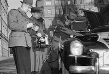Polismännen Axelsson och Remblad från Gengaspolisen undersöker ett gengasläckage i en bil med hjälp av en koloxidindikator. T.h. Ingenjör Sieurlin från Gengasbyrån
