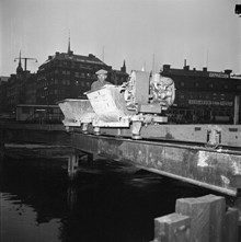 Norrström. Arbetsvagn på spår över vattnet i samband med byggnation. I fonden Tegelbacken