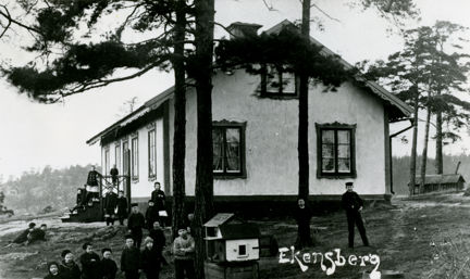 Arbetarbostaden Ettan vid Ekensbergs varv, omkring 1900, med vuxna och barn framför huset.