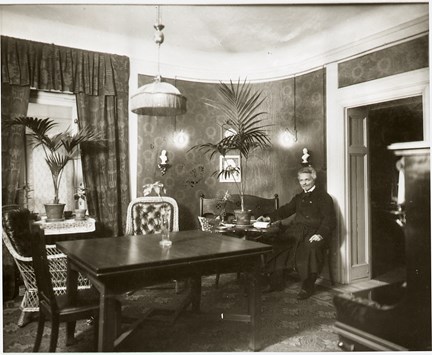 Svartvitt fotografi. August Strindberg sitter på en stol i sin matsal