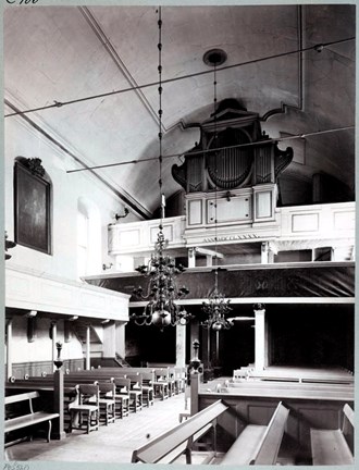 Svartvit bild på interiören i Finska kyrkan, tagen från altaret mot bänkraderna och orgelläktaren.