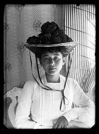 Porträttfotografi av Strindbergs hustru Harriet Bosse i Furusund, iklädd vit klänning och och stor hatt.