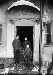 Artillerigatan 31. Tre pojkar står vid porten till gårdshuset