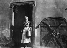 En kvinna står i dörröppningen till gården vid Bondegatan 4, nuvarande 10. Dörren av järn leder till källaren