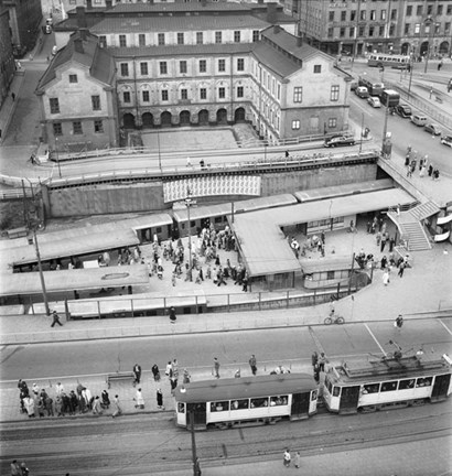 Det är mindre än två år sedan tunnelbanan invigdes i Stockholm, 1 oktober 1950, när bilden togs. Tunnelbanestationen Slussen är vid denna tidpunkt en öppen station. I bakgrunden ser vi Stadsmuseet i Stockholm. 
