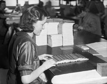 Kvinnor sorterar och kontrollerar motböcker. Bilden är tagen i samband med motbokssystemets 25-år jubileum år 1939.