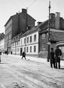 En polis med kask och sabel samtalar med en man. Skånegatan västerut från Nytorgsgatan. Skånegatan 19, 17 och 15. Nu Skånegatan 75-73