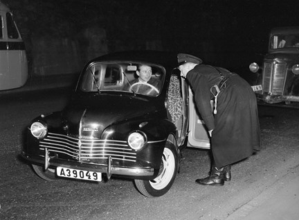 En polis lutar sig in i en Renault, där en man sitter vid ratten.