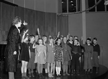 Ringvägen 58, Eriksdals folkskola. Barn demonstrerar berättande sång tillsammans med sin lärarinna, under småskollärarinneförbundets kurs i sångundervisning