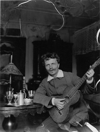 Svartvitt fotografi av August Strindberg spelandes gitarr, vid ett bord uppdukat med absint