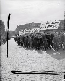 Demonstrationståg med banderoller "Mot nazisim och judeförföljelse" och "För frihet, arbete och demokrati" på Värtavägen mot Valhallavägen. I fonden kvarteret Djursborg.