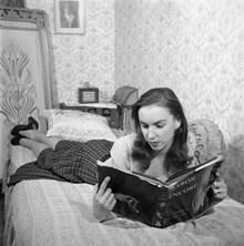 Porträtt av balettdansösen Mariane Orlando i sitt hem, läsandes en bok i sängen. Orlando blev år 1953 premiärdansös vid Operan, med sina 19 år den yngsta dittills