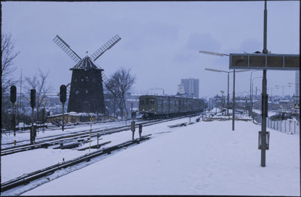 Gullmarsplan i vinterskrud när ett tunnelbanetåg passerar väderkvarnen och rullar in mot perrongen år 1977