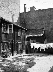 Tvätt hänger på tork över gården vid Styrmansgatan 20 (nuvarande 16). Trähuset omges av brandmurar