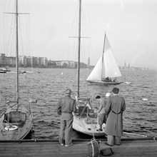 Kajen vid Söder Mälarstrand. Några män vid en segelbåt. Riddarfjärden och Norr Mälarstrand i fonden