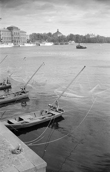 Vid Strömkajen ligger båtar med fiskehåvar. Nationalmuseum i fonden