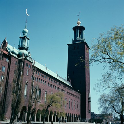 Bild från markplan med Stadshustornet i centrum. Träd grönskar till höger i bild och himlen är blå utan moln.