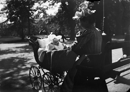 Kvinna i Humlegården med ett litet barn i barnvagn.
