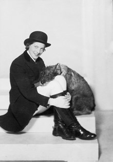 Porträtt av kvinna, Lollo, i riddräkt med stövlar, tillsammans med sin hund