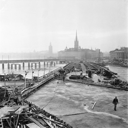 Byggnation av tunnelbanebron mellan Slussen och Gamla Stan. I förgrunden Sjöbergsplan och i fonden Riddarholmen och Riddarholmskyrkan.