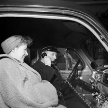 Taxichaufför Einar Söderberg demonstrerar en taxiradioanläggning hos Huddingetaxi för passageraren fröken Henriksson