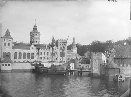 Slott med torn, skepp tillagt vid brygga, sett från andra sidan vattnet