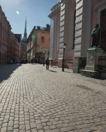 Foto taget på dagtid av kullerstenar med en kyrka i bakgrunden. 