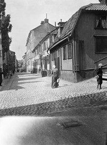En kvinna går Tavastgatan västerut från Timmermansgatan. T.h. Tavastgatan 30-34. Tavastgatan 32, lumpaffären, revs 1910